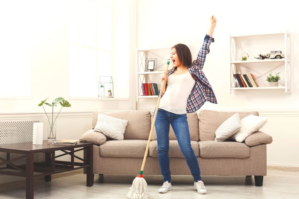 a girl dancing joyfully with broom after getting rid of clutter